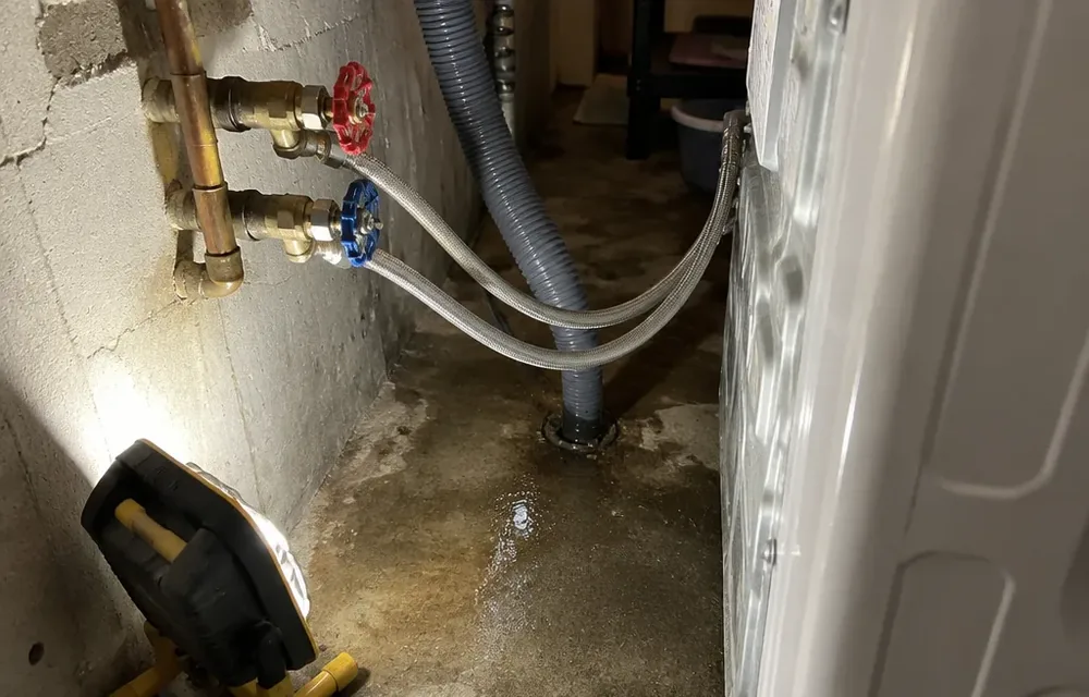 Washing machine supply hoses and valves with water on laundry floor